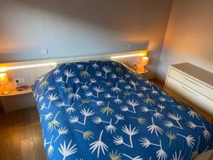 um quarto com uma cama com um cobertor azul e branco em 't Genot em Blankenberge