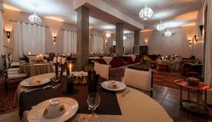 un restaurante con mesas, sillas y lámparas de araña en HOTEL Bab Rimal en Foum Zguid