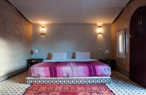a bedroom with a large bed in a room with two lamps at HOTEL Bab Rimal in Foum Zguid