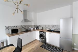 a kitchen with white cabinets and a washer and dryer at Les Nuits Bonneuilloises Le Henson in Breteuil