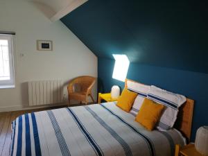 a bedroom with a blue wall and a bed with yellow pillows at A deux pas d'la mer in Grandcamp-Maisy