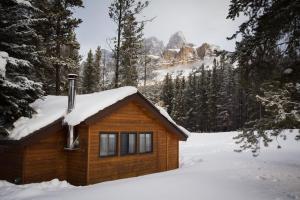 a log cabin with snow on the roof at Castle Mountain Chalets in Castle Junction