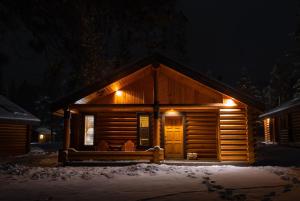 una cabaña de madera por la noche en la nieve en Castle Mountain Chalets, en Castle Junction