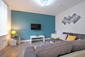 a living room with a couch and a blue wall at 5* Luxury 1 Bedroom Apartment in City Centre in Aberdeen