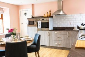 a kitchen with a dining table and a kitchen with pink walls at Bramble Cottage in Turriff