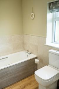a bathroom with a white tub and a toilet at Bramble Cottage in Turriff