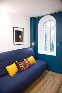 um sofá azul num quarto com uma janela em CHARMING Parisian Apartment WITH AIR CONDITIONING - CLIMATISATION & 2 BEDROOMS - Batignolles PARIS em Paris