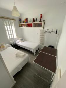 a room with two beds and a table in it at Habitaciones la viña in Cádiz