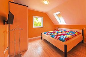 SeehausenFerienhaus Hyggelig in Seehausen am Oberuckersee的一间卧室设有橙色的墙壁和一张带电视的床。