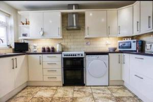 a kitchen with white cabinets and a dishwasher at Large 4 Bedroom House in Central Coventry in Walsgrave on Sowe