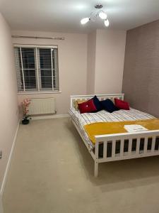 a bedroom with a bed with red and blue pillows at Luxurious & Cosy Apartment in Surrey in Weybridge