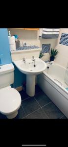 a bathroom with a toilet and a sink and a tub at Largs Holiday Apartment in Largs