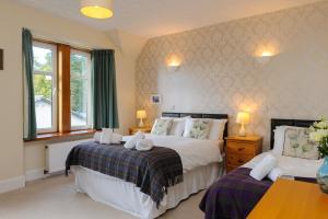 a bedroom with two beds and two windows at Alvey House in Newtonmore