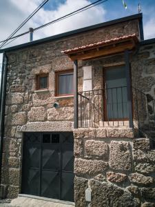 ein Steinhaus mit einer grünen Garagentür in der Unterkunft Casa dos Trenós in Sabugueiro