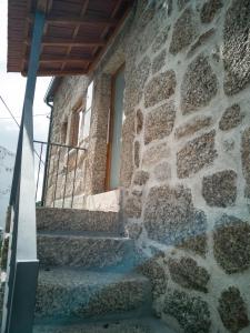 un edificio de piedra con escaleras que conducen a una ventana en Casa dos Trenós, en Sabugueiro