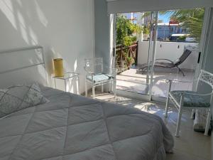 1 dormitorio con 1 cama y sillas en el balcón en Brisas 1 en Santa Teresita