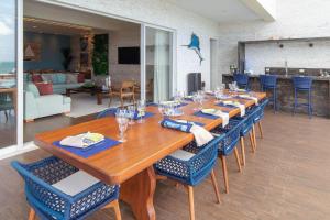 una larga mesa de madera con sillas azules en una habitación en Luxo na beira mar de Porto Mirim RN por Carpediem, en Jacumã