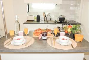 a table with two plates of food and glasses of orange juice at Joli studio tout confort à 2 pas de la gare Poissy in Poissy