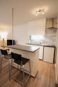 a kitchen with a counter and chairs in a room at Joli studio tout confort à 2 pas de la gare Poissy in Poissy