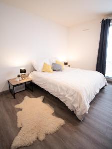 a bedroom with a white bed with a rug on the floor at Joli studio tout confort à 2 pas de la gare Poissy in Poissy