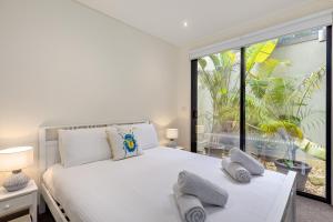 a bedroom with a white bed and a large window at Seaside Luxury Accommodation in the Heart of Rye in Rye