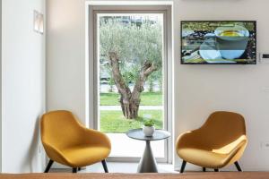 twee stoelen en een tafel voor een raam bij Portone180 Guest House in Roveredo in Piano