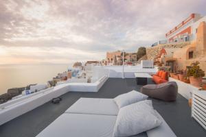 balkon z białymi meblami i widokiem na wodę w obiekcie Sophia Privilege w mieście Oia