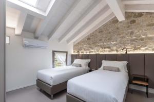 two beds in a room with a stone wall at Portone180 Guest House in Roveredo in Piano