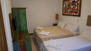 a room with two beds and a television in it at Pousada João Sol in Praia do Forte