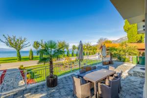 eine Terrasse mit einem Tisch, Stühlen und einer Palme in der Unterkunft Risteski Apartments - St. Naum in Ohrid