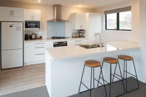 a kitchen with white cabinets and a large island with stools at Shepherd's View - Lake Tekapo in Lake Tekapo