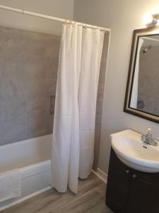 a bathroom with a white shower curtain next to a sink at Gateway Motel in Gananoque