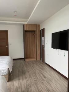 a hotel room with a bed and a flat screen tv at Ferry Head Leisure Club in Yuanshan