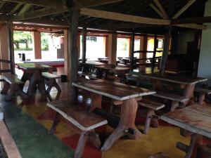 um grupo de mesas e bancos de madeira numa sala em Águas Vivas Hotel Fazenda em Pirenópolis
