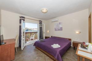 a bedroom with a purple bed and a balcony at Rooms Zdravko in Stara Novalja