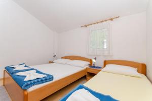 2 aparte bedden in een kamer met witte muren bij Apartments Zoran in Drvenik