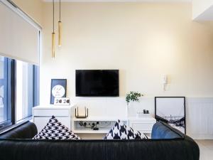 ein Wohnzimmer mit einem schwarzen Sofa und einem TV in der Unterkunft Tropicana 218 Macalister Studio with Seaview in George Town