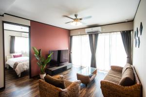 a living room with a couch and chairs and a bed at ヴィラ・アカバナー　B棟 in Miyako Island