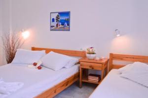 duas camas num quarto com uma mesa de cabeceira entre elas em Helen's Budget Accommodation em Agkairia