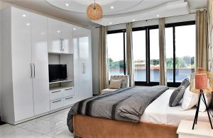a bedroom with a large bed with a tv and windows at Résidence L'écrin in Yaoundé +227 photos