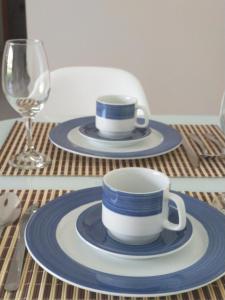 a table with two plates and a cup and a glass at Palm Village Acqua - Apartamento Premium - Em frente à piscina - Porto de Galinhas in Porto De Galinhas