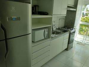 cocina blanca con nevera y microondas en Palm Village Acqua - Apartamento Premium - Em frente à piscina - Porto de Galinhas en Porto De Galinhas