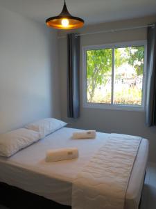 a bed with two pillows on it in a room with a window at Palm Village Acqua - Apartamento Premium - Em frente à piscina - Porto de Galinhas in Porto De Galinhas