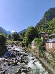 a river with rocks and buildings next to a mountain at Morféo-le Vignemale in Cauterets