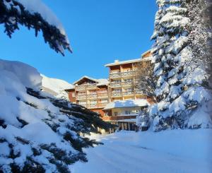 un lodge de ski dans la neige avec des arbres enneigés dans l'établissement Hôtel du Hameau, à La Foux