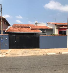 uma casa com um portão preto em frente a uma rua em Casa Premiatto em Holambra