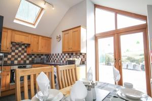 a kitchen with wooden cabinets and a table with chairs at Pendre Uchaf in Derwen