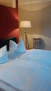 a large white bed in a room with a lamp at Hotel und Gasthof Dreibeiniger Hund in Görlitz