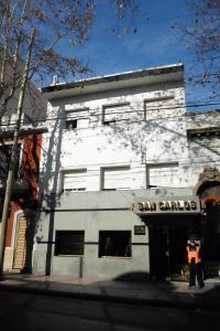 Un uomo in piedi di fronte a un edificio bianco di Hotel San Carlos a Buenos Aires