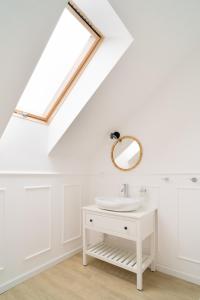 ein weißes Badezimmer mit einem Waschbecken und einem Spiegel in der Unterkunft Nad jeziorem Nagus w Toruniu in Toruń